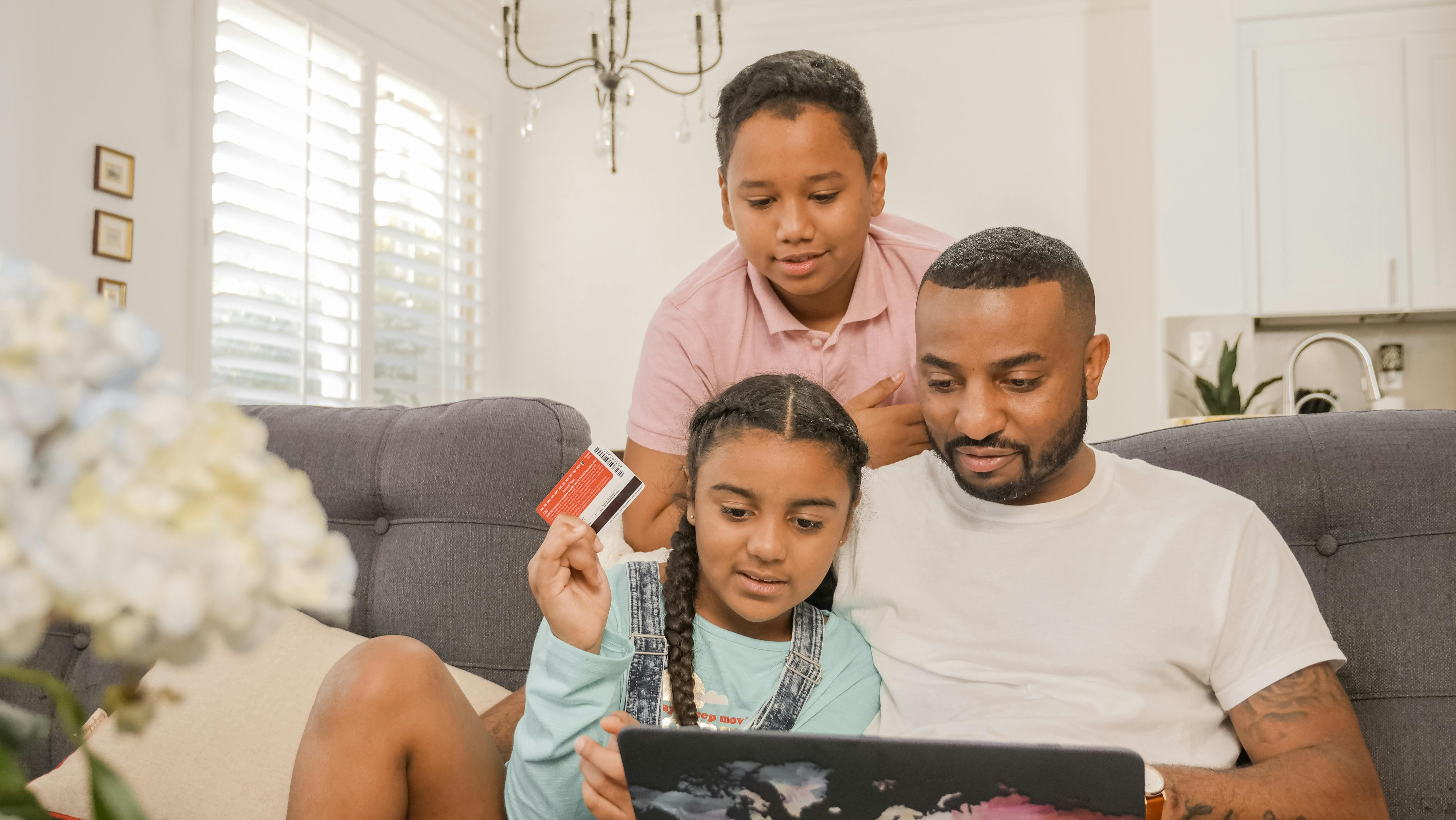 Two 6 to 9 year old girls with their father, learning on a laptop